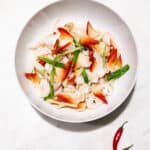 Hokkigai arctic surf clams stir fry with ginger and scallions in white bowl garnished with cilantro