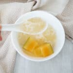 Chinese Papaya Dessert with Snow Fungus in a white bowl and close up of the dessert in spoon
