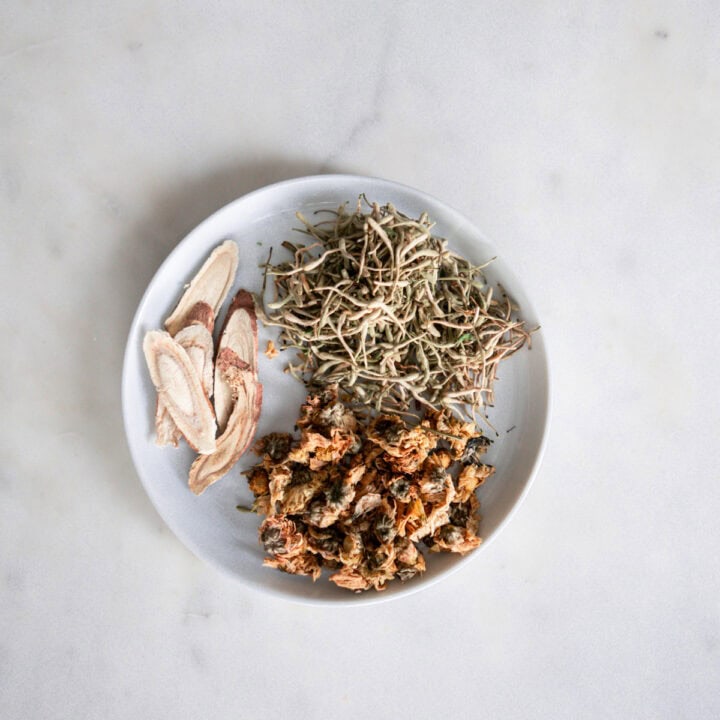 close up of Dried chrysanthemum flowers, honeysuckle buds, and licorice root ingredients for traditional Chinese cooling tea recipe