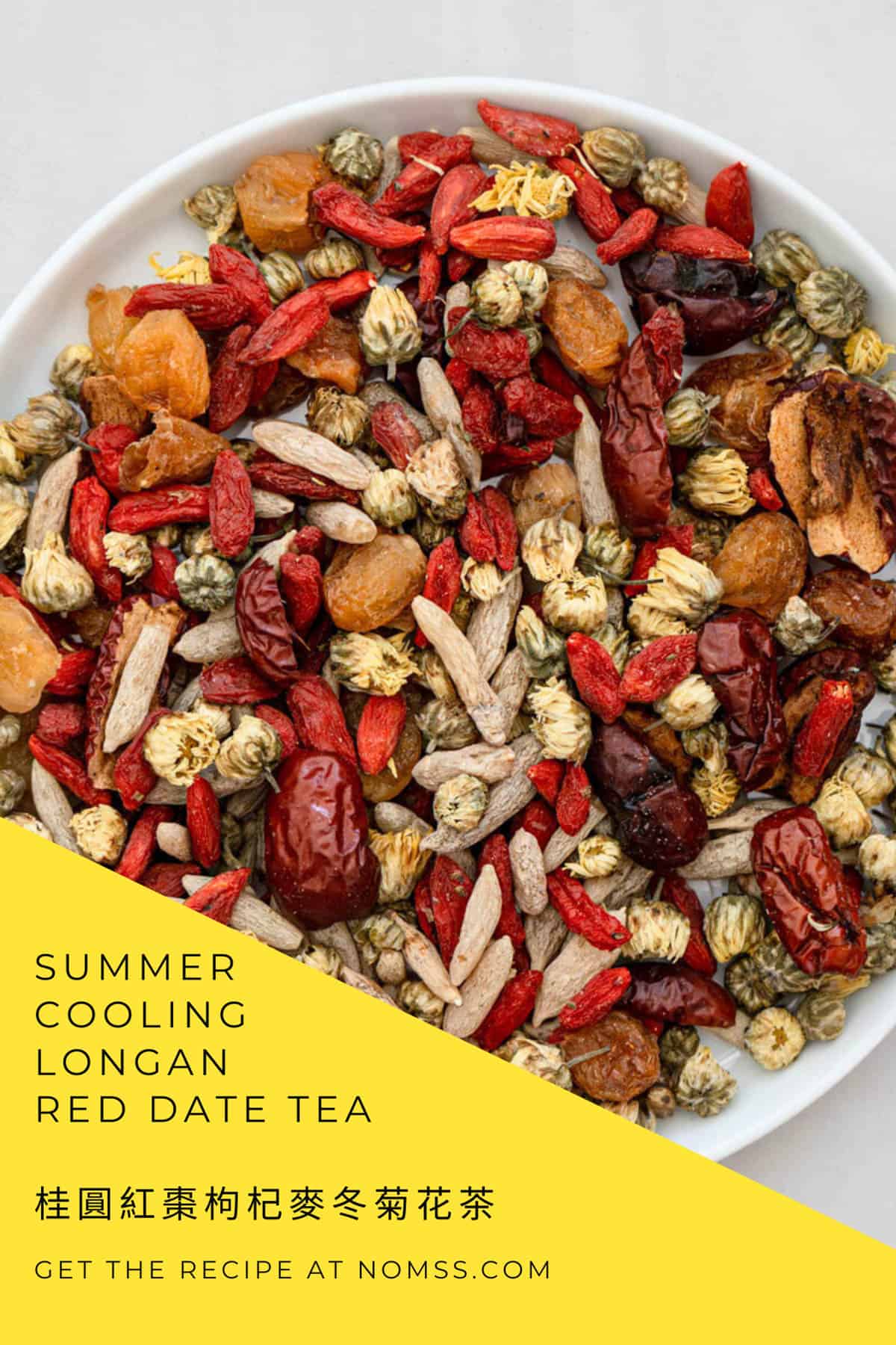 Cooling summer longan date tea in glass teacup with chrysanthemum flowers and goji berries on wooden table