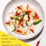 Hokkigai arctic surf clams stir fry with ginger and scallions in white bowl garnished with cilantro