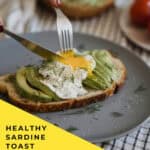 cutting poached egg on top of Close up of sardine avocado toast garnished with cilantro and lemon juice