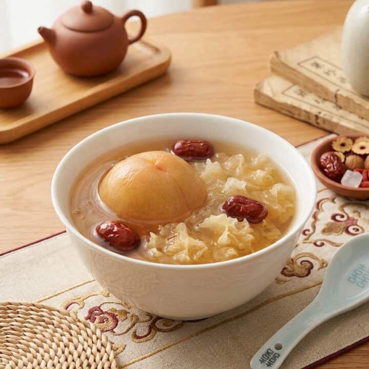 Stewed peach snow fungus red dates dessert soup in white ceramic bowl with goji berries